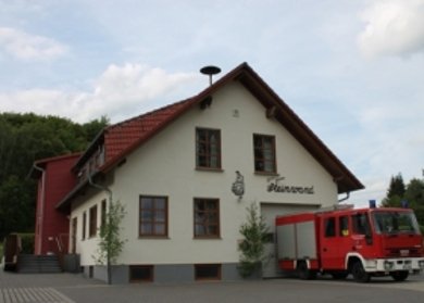 Feuerwehrhaus Steinwand Feuerwehrhaus Steinwand mit Fahrzeug vor dem Gebäude und großem Wandmotiv.